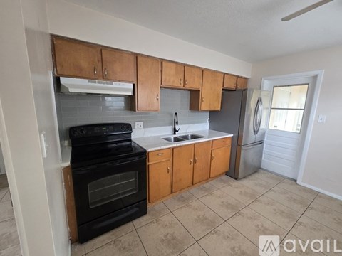 A kitchen with black appliances and wooden cabinets.