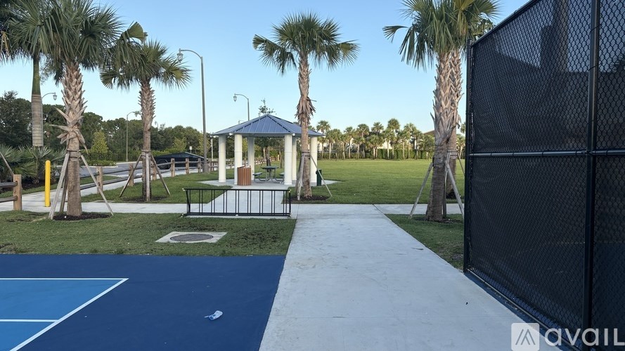 A basketball court with a gazebo and palm trees in the background.