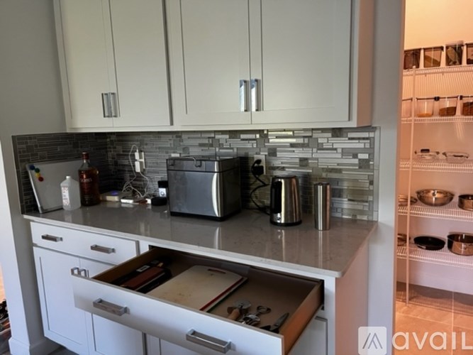 A kitchen with white cabinets and a marble countertop.