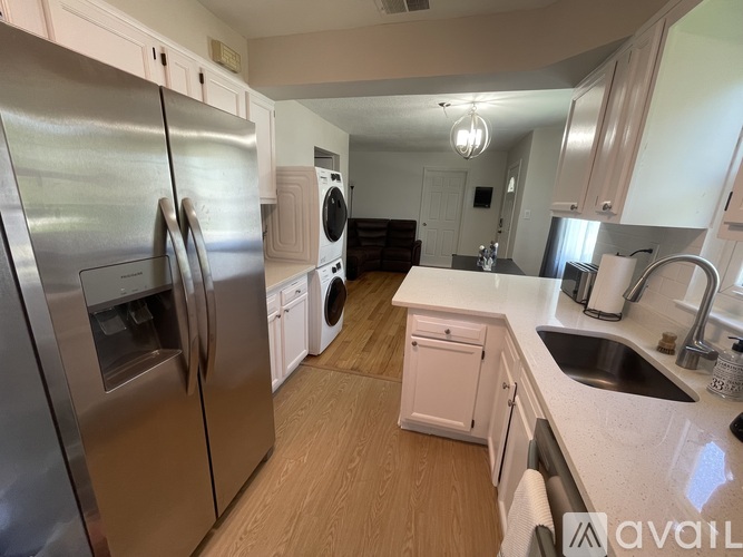 A kitchen with a refrigerator, washing machine, and a sink.
