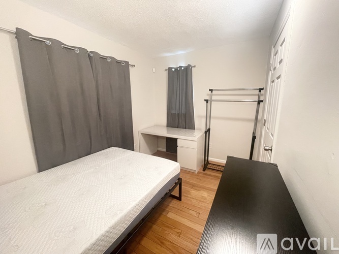 A bedroom with a bed, a bench, and a black table.