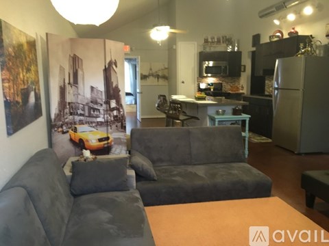 A living room with a grey couch and a kitchen area in the background.