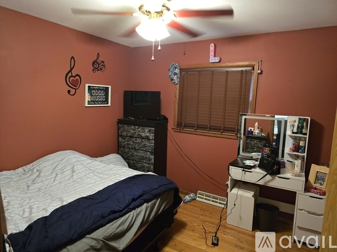 A bedroom with a bed, desk, and ceiling fan.