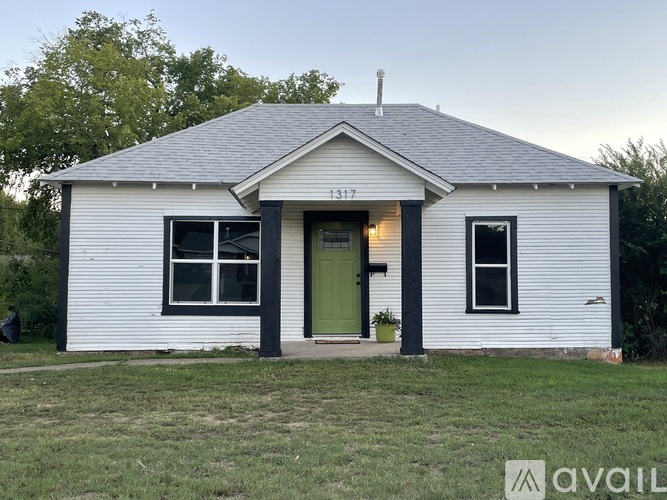 A small white house with a green door and a black trim.