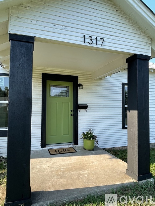 A white house with a green door and a number 1317 on the wall.
