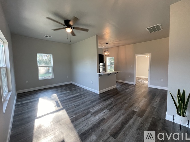 A spacious room with wooden flooring and a ceiling fan.