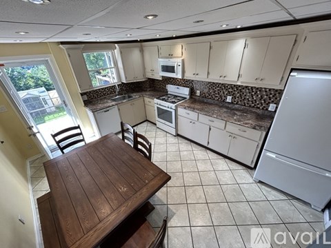 A kitchen with a wooden table and white appliances.