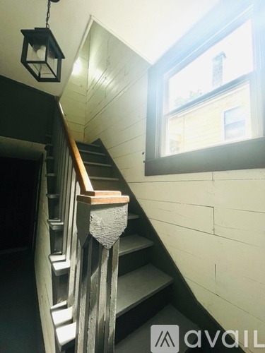 A staircase with a wooden handrail and a window on the wall.