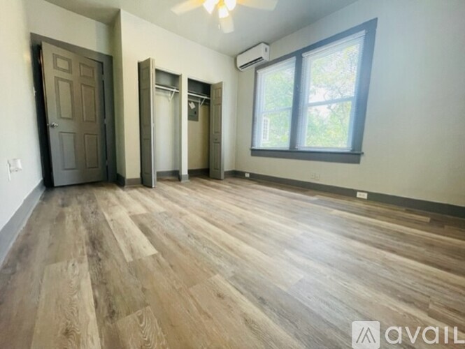 A room with wooden flooring and a window with a view of trees.