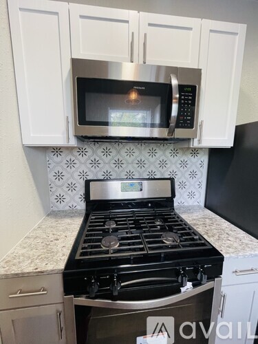 A kitchen with a black stove top oven and a microwave above it.