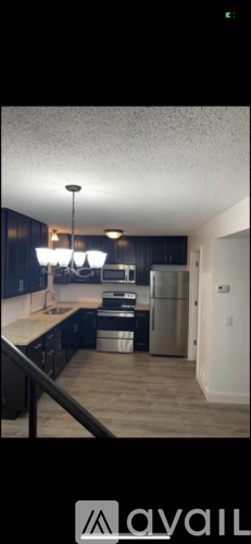 A kitchen with dark wood cabinets and a stainless steel refrigerator.