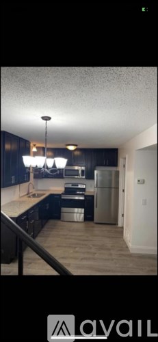 A kitchen with dark wood cabinets and a stainless steel refrigerator.