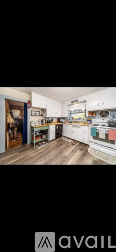 A kitchen with white cabinets and a wooden floor.