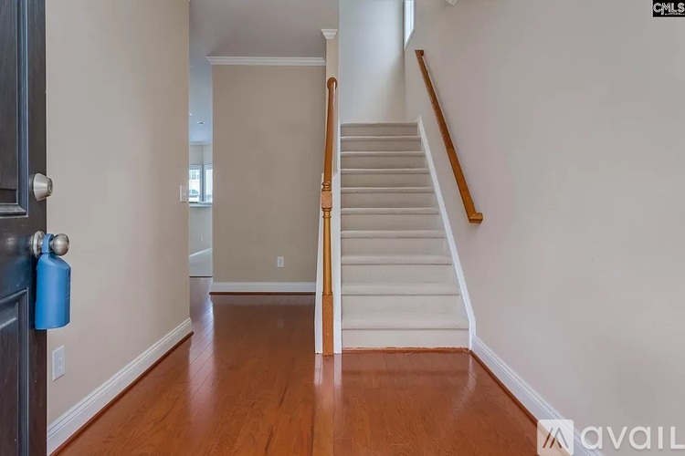 A hallway with a staircase and a blue container on the floor.
