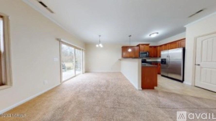 A spacious living room with a kitchen area in the background.