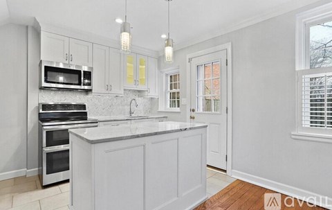 A kitchen with white cabinets and a wooden floor.