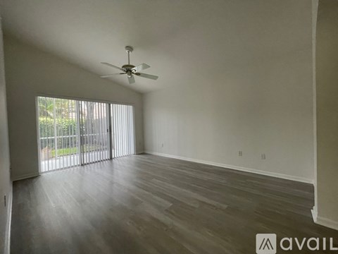 A spacious room with a ceiling fan and sliding glass doors.