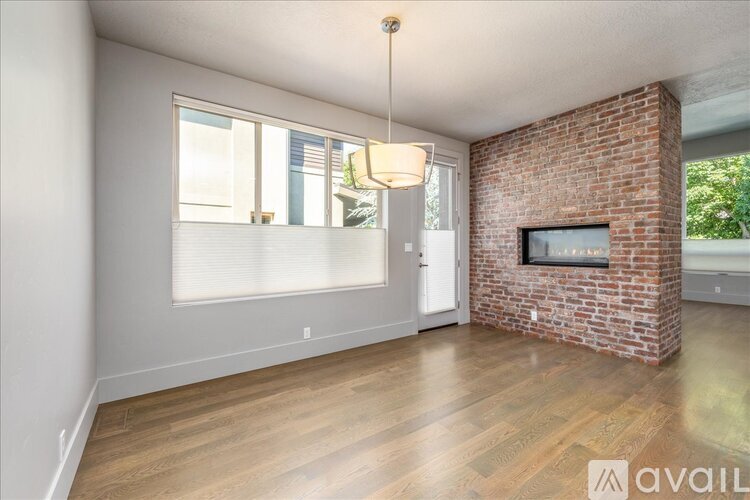 A living room with a brick fireplace and a wooden floor.