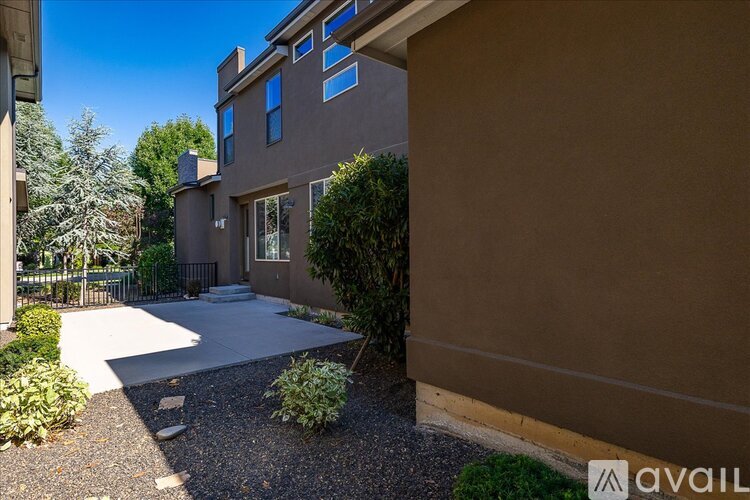 A modern house with a brown exterior and a gravel driveway.