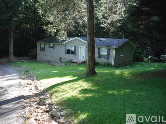 A house with a green lawn and trees in the background.