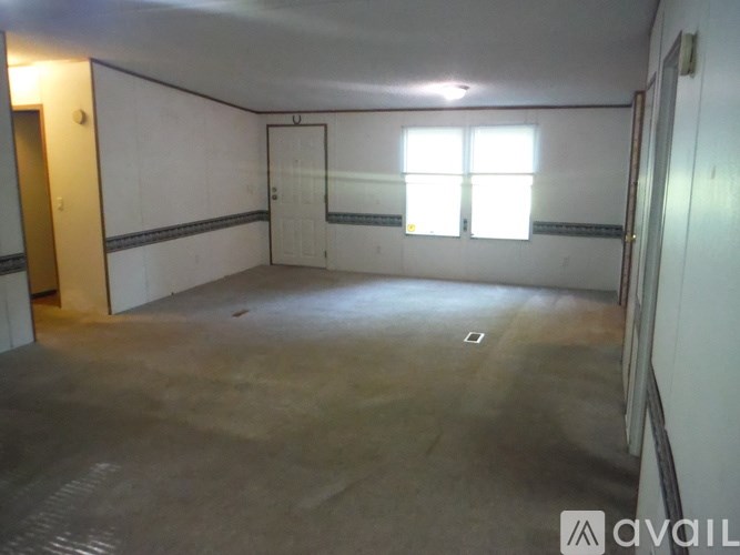 A large empty room with a window and a door.