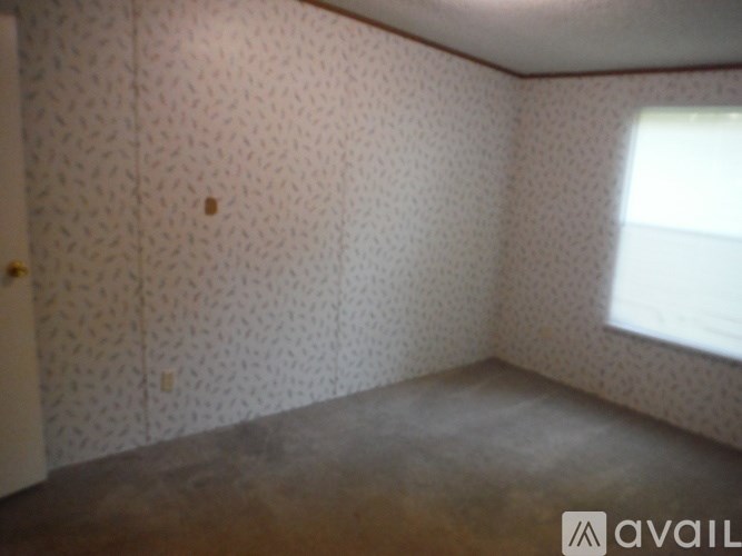 A room with a window and wallpapered walls.