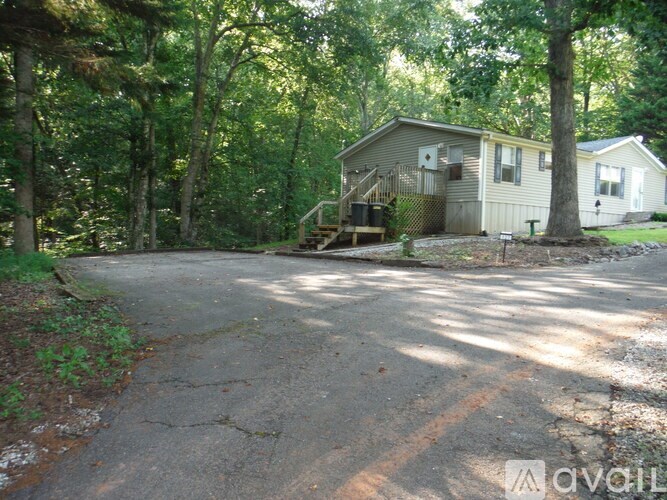 A house is surrounded by trees and has a driveway in front.