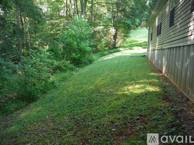 A grassy path leads to a house in a wooded area.