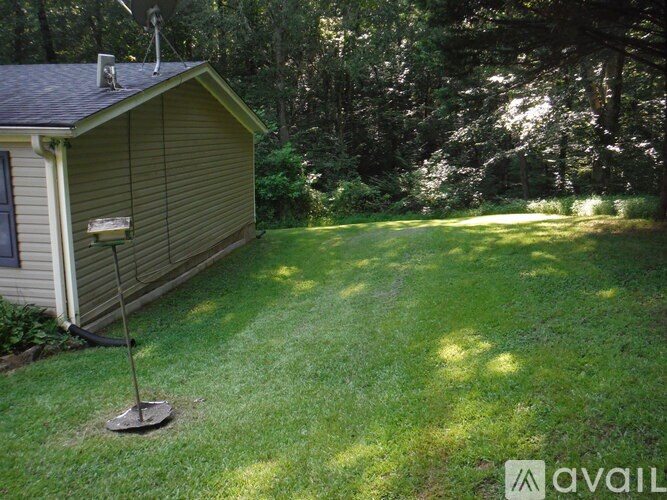 A small house with a satellite dish on the roof is surrounded by a grassy lawn.