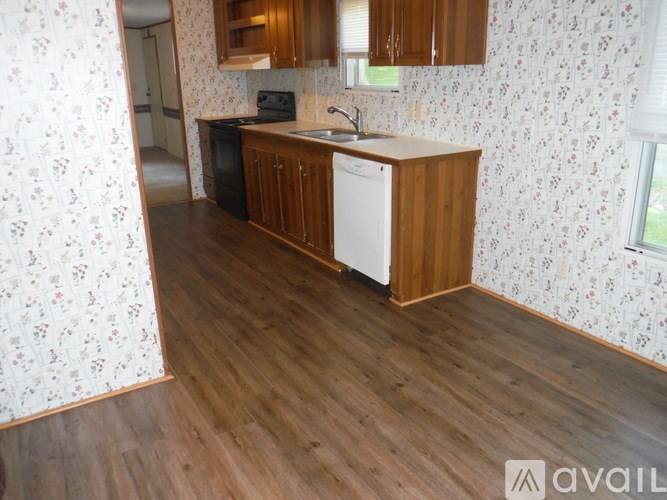 A kitchen with wooden floors and floral wallpaper.