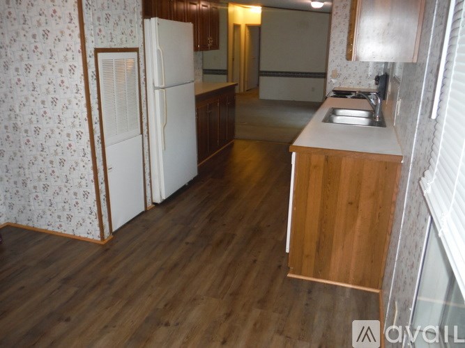 A kitchen with a white fridge and wooden floors.