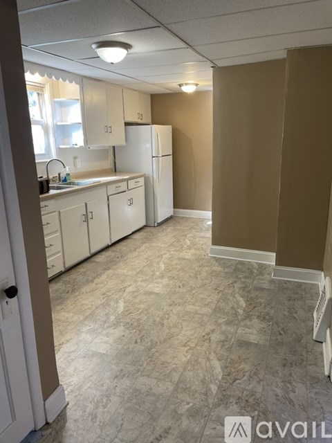 A kitchen with white cabinets and a marble floor.