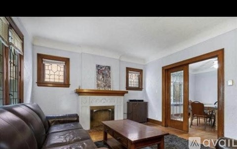 A living room with a brown leather couch and a fireplace.