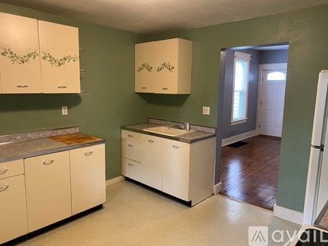 A kitchen with white cabinets and a green wall.