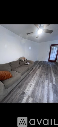 A living room with a grey couch and a wooden floor.