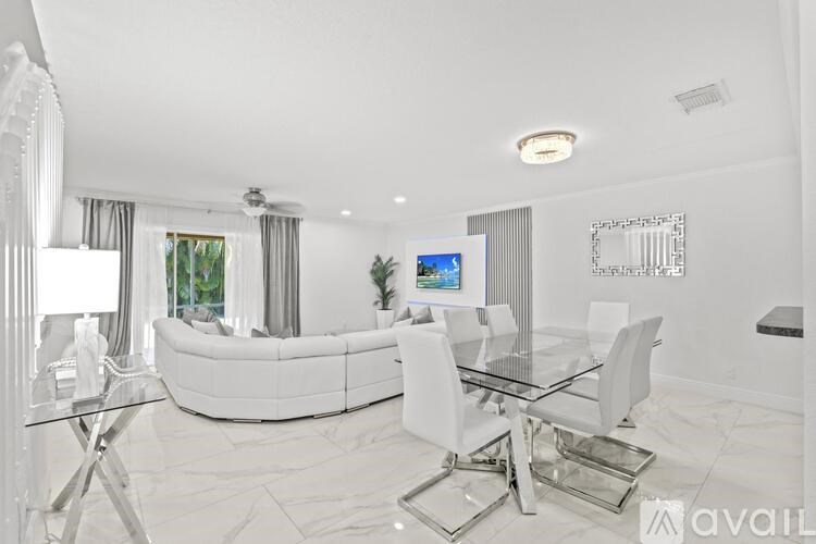 A modern living room with a glass table and white furniture.
