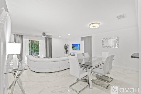 A modern living room with a glass table and white furniture.