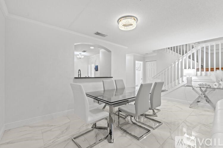 A modern dining room with a glass table and white chairs.