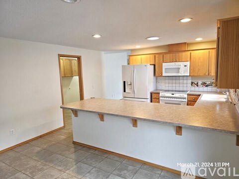 A kitchen with a white refrigerator and wooden cabinets.
