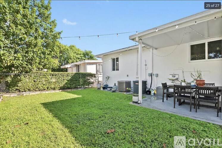 A white house with a green lawn and a patio table.