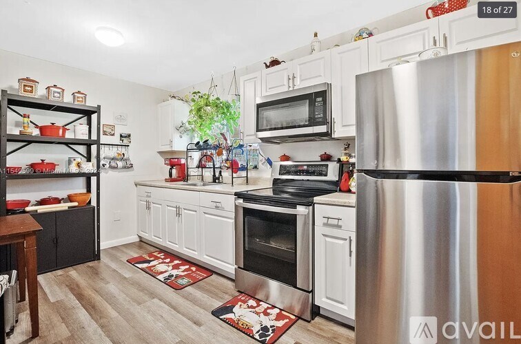 A kitchen with white cabinets and a stainless steel refrigerator.