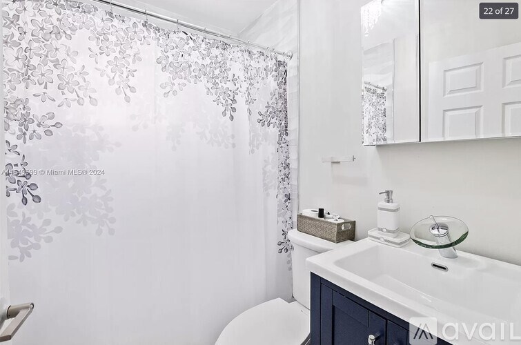 A white bathroom with a shower curtain and a white sink.