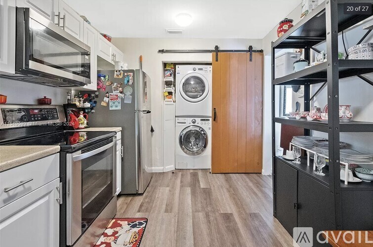 A kitchen with a washing machine in the doorway.