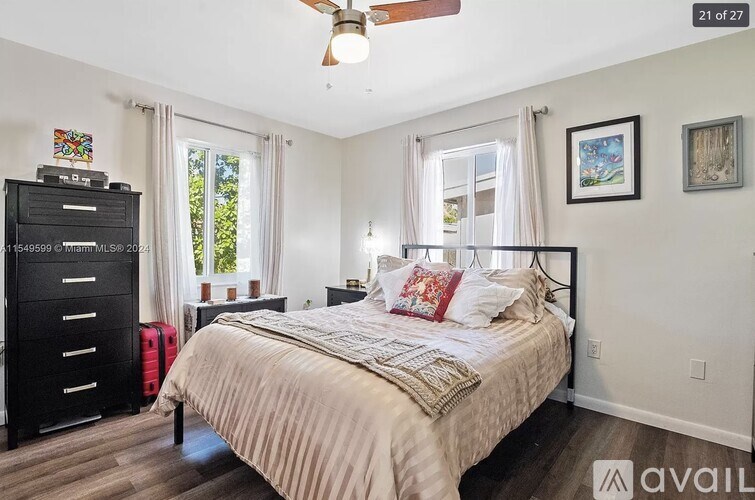 A bedroom with a large bed, a dresser, and a ceiling fan.