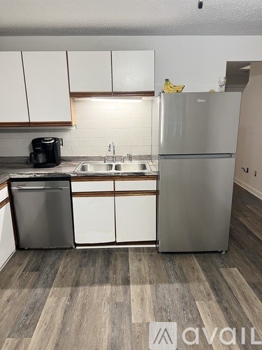 A kitchen with a refrigerator, sink, and dishwasher.