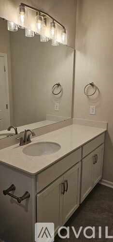 A bathroom with a vanity and a mirror with lights.