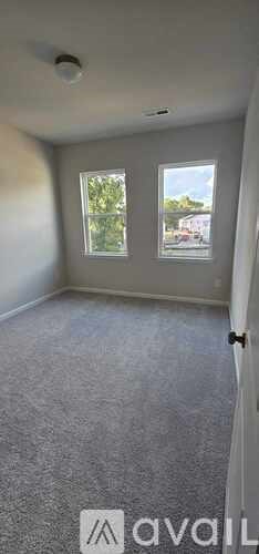 A room with two windows and a car visible through the window.