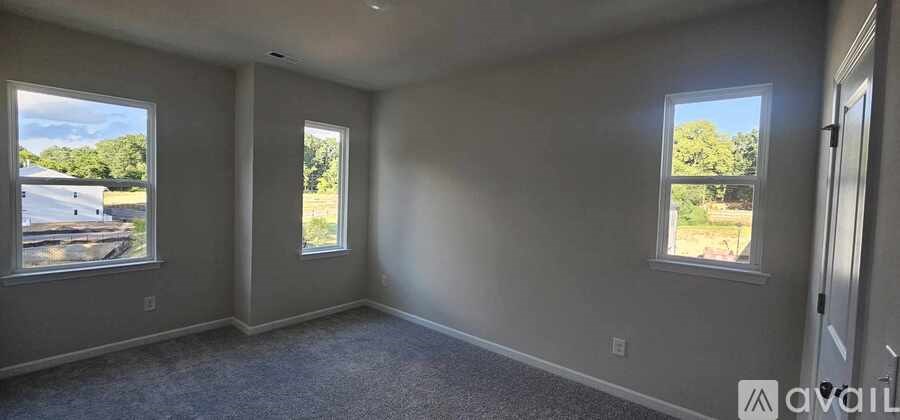 A room with three windows and carpeted floor.