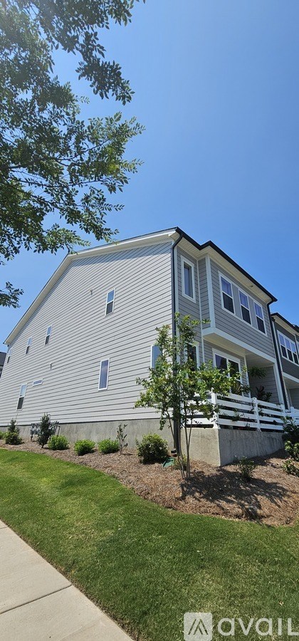 A house with a well-maintained lawn and a clear blue sky above.