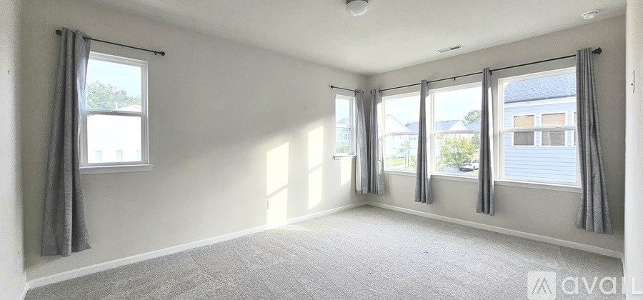 A room with grey carpet and grey curtains.